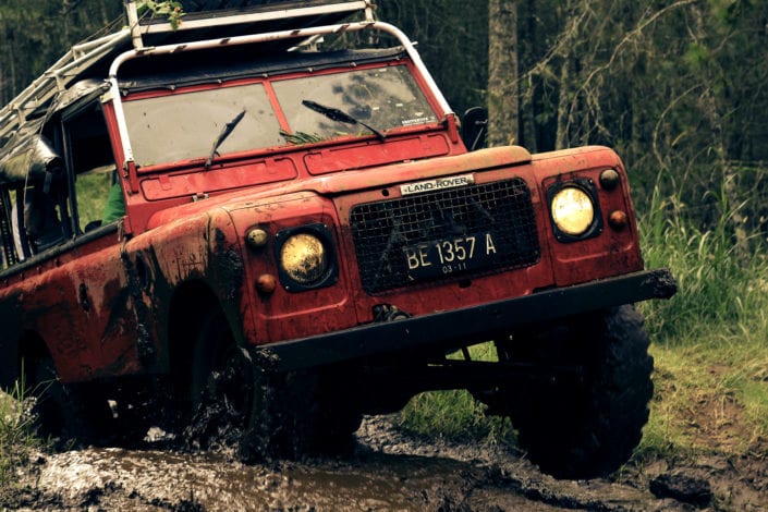 a red jeep driving a the forest