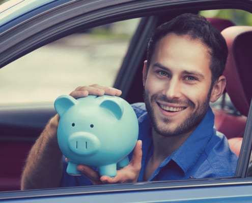 a man holding a blue piggie bank while sitting in his car
