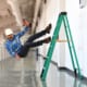 a worker holding a drill falling of a ladder