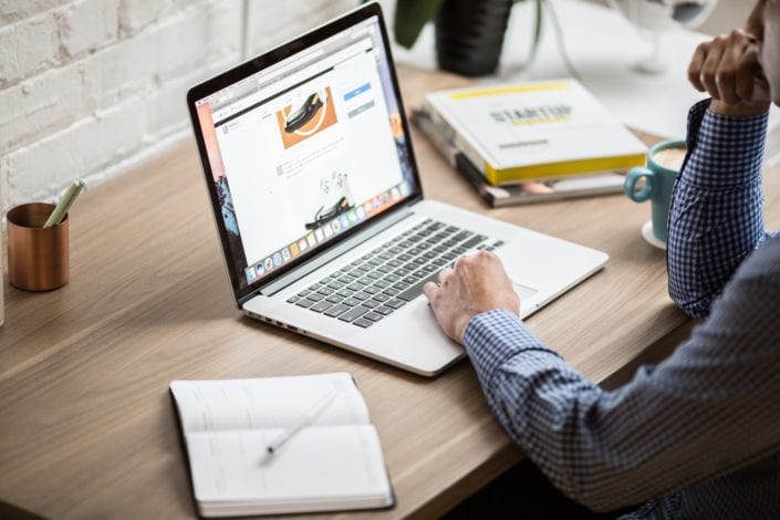 Small business owner working on laptop reviewing business insurance options