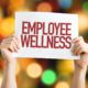 a person holding a employee wellness sign
