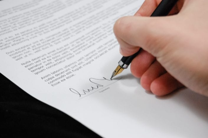Person signing business insurance policy document