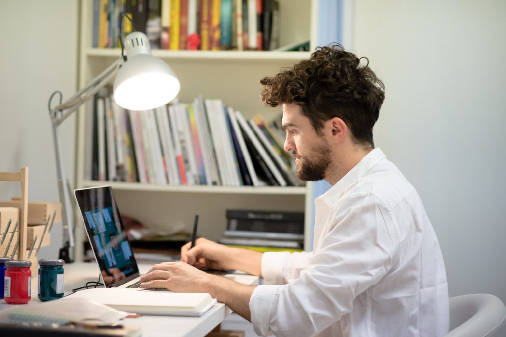 person at his work table working on his laptop