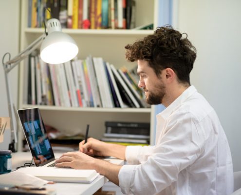 person at his work table working on his laptop