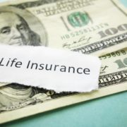 life insurance written on a page placed on top of two hundred dollar bills