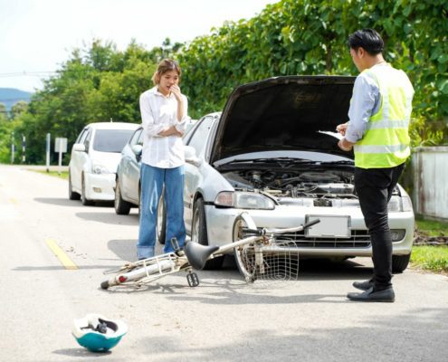 Insurance adjuster assessing car and bicycle accident damage on roadside