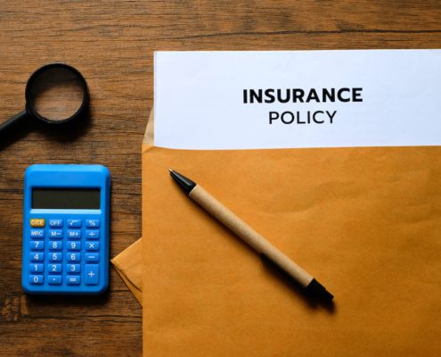 insurance policy papers in a brown envelop with a pen and calculator on the table
