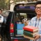 Student moving into dorm with books and belongings in car trunk
