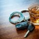 car keys, handcuffs and a glass of whiskey on a table