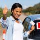 New driver holding license with learner sign on car window