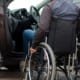 Person in a wheelchair transferring into the driver’s seat of a vehicle.