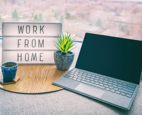 Work from home office setup with laptop and sign
