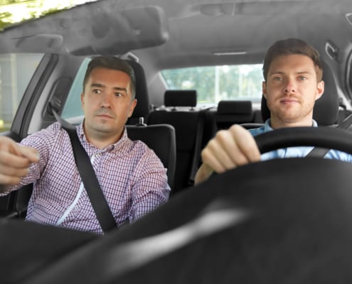 two guys sitting in a car while drives and one gives direction