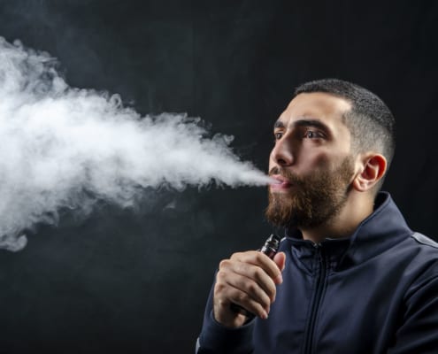 a guy vaping with smoke blowing out of his mouth