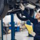 Auto mechanic inspecting car exhaust system on vehicle lift in repair shop