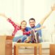 young couple sitting in their new house with moving boxes around them