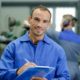 a man writing on a clipboard in a factory