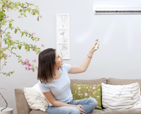 a woman turning on her ac with a remote sitting in her lounge