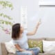 a woman turning on her ac with a remote sitting in her lounge