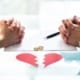 Hands of couple over divorce paperwork with rings and broken heart