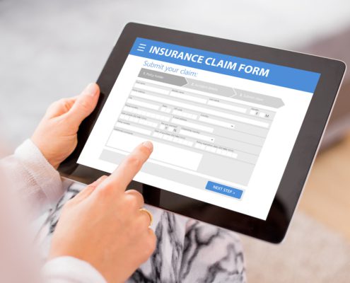 Person submitting insurance claim form online on tablet screen