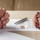 Couple sitting across from each other with divorce papers and wedding ring on table