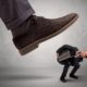a boot stomping a man in a suit