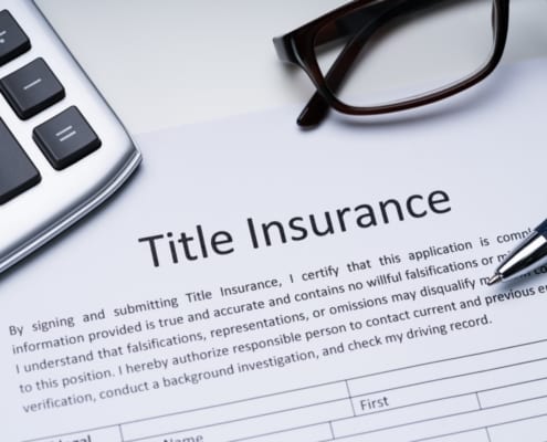 Title insurance document on desk with calculator, pen, and eyeglasses