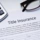 Title insurance document on desk with calculator, pen, and eyeglasses