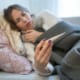 woman laying in a bed looking at a thermometer