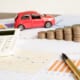 a car model, pennies, calculator and a pen over pages placed on a table