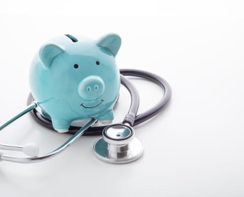 Blue piggy bank sitting inside a stethoscope on a white background.