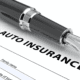 Auto insurance document with fountain pen and miniature car.