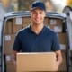 a delivery driver holding a box and smiling into the camera