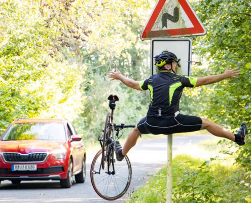 Cyclist losing control and colliding with road sign while car approaches
