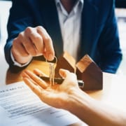 a real estate agent handing keys to a person who just signed his new house agreement