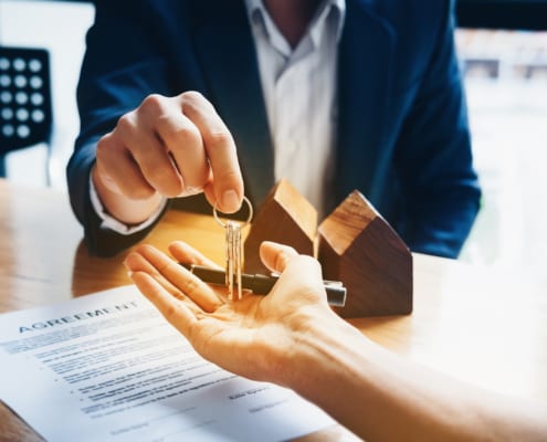a real estate agent handing keys to a person who just signed his new house agreement