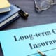 Document labeled “Long-term Care Insurance” on a desk with books, a pen, and eyeglasses