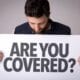 a guy holding a sign saying "are you covered?"