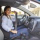 woman sitting in her car putting on her seat belt