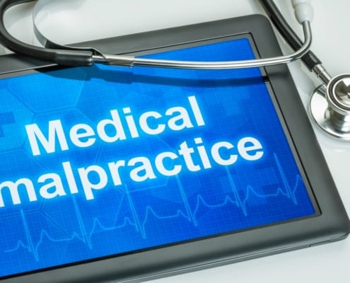 medical malpractice written on an ipad on a table with stethoscope on it