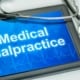 medical malpractice written on an ipad on a table with stethoscope on it