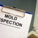 a mold inspector inspecting a house with a clipboard in his hand