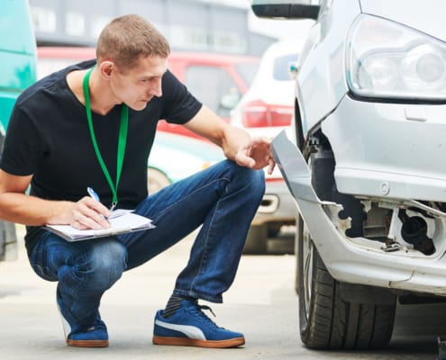 insurance agent inspecting a broken car bumper