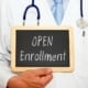 a doctor holding a sign with "open enrollment" written on it