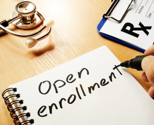 a notepad on a table with open enrollment written on it with doctor equipment on the table