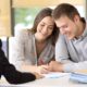 happy couple sitting with a insurance agent signing renters liability papers