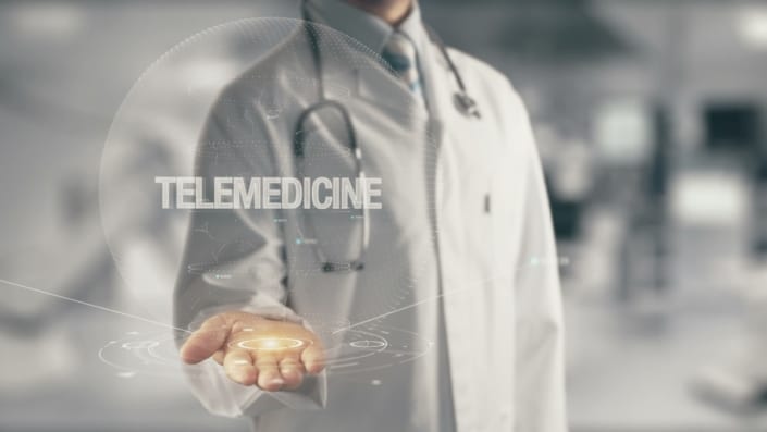 a doctor holding a graphic globe saying telemedicine in his hand