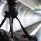 Person holding duffel bag on subway platform with train tracks in background