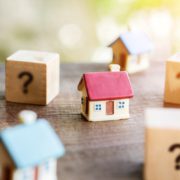 Small model house surrounded by question mark blocks on wooden table